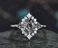 an engagement ring with a fancy diamond center stone in white gold, setting on top of a rock