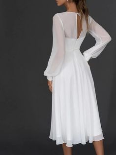 a woman wearing a white dress with long sleeves and open back, standing in front of a