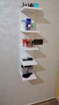 three white shelves with cosmetics and toiletries on them against a wall in a bathroom