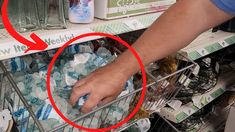 a person is picking up bottled water from the shelf in a grocery store, with an arrow pointing to it