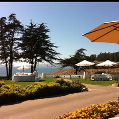 an outdoor dining area with tables and umbrellas overlooking the ocean on a sunny day