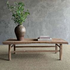 a wooden table topped with a vase filled with green plant sitting on top of it