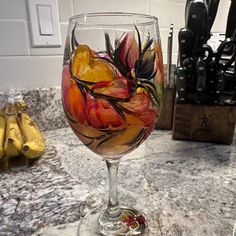 a glass filled with liquid sitting on top of a counter next to bananas and knifes