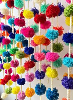 multicolored pom - poms hanging from ropes on the wall