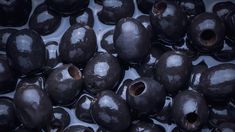 some black olives are sitting in a bowl with ice on it's surface