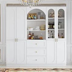 a room with white cupboards, chandelier and rug on the floor in front of it