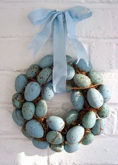 a wreath made out of eggs hanging on a brick wall next to a blue ribbon