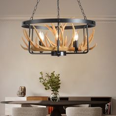 a chandelier hanging over a dining room table with two chairs and a vase filled with flowers