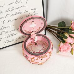 a pink box sitting next to a bouquet of roses and a note with the word love written on it