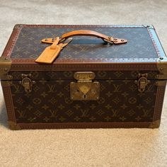 an old louis vuitton trunk is sitting on the floor with a leather handle