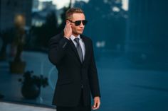 a man in a suit and sunglasses talking on his cell phone