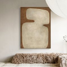 a painting hanging on the wall above a couch in a room with white walls and fur pillows