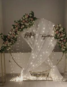 a wedding arch decorated with flowers and fairy lights for the entrance to the ceremony room