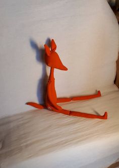 an orange toy sitting on top of a white bed