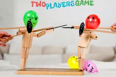 two players game with wooden sticks and plastic balls in the shape of people pulling each other's strings