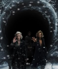 three people standing in front of a dark tunnel with snow falling on the ground and one person waving