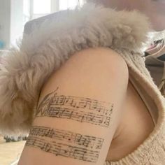 a woman with a tattoo on her arm that has sheet music notes written on it