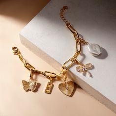 Add a personalized touch to your accessories with our Cami Initial Charm Bracelet. Featuring large charms with your chosen letter, this bracelet is the perfect combination of style and individuality. Express yourself with our unique and fun design! Available in 14k gold plated brass Palmer Initial Charm: 5/8" tall, width varies Cami Butterfly Charm: 13/16"x 5/8" Cami Heart Charm: 3/5"x 13/16" with 2 mm round cubic zirconia stone Cami Bow Charm: 3/5"x 11/16" with 1.5mm x 3mm cubic zirconia baguet Tennis Jewelry, Initial Charm Bracelet, Modern Jewellery Design, Bow Charm, Jewelry Wardrobe, Gold C, Wardrobe Goals, Gold Charm Bracelet, Pearl Charms