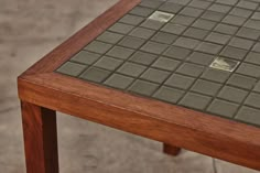 a close up of a wooden table with tile on it's top and bottom