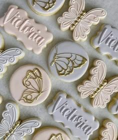 decorated cookies with the words victoria and butterflies in gold, white, and pink frosting