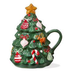 a green ceramic christmas tree mug with ornaments on it's side and a gold star