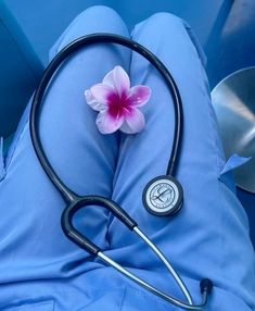 a stethoscope laying on top of a blue pillow next to a pink flower