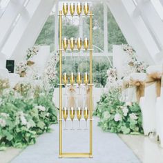 a tall display case filled with champagne glasses in front of a white and gold wedding arch