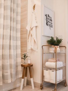 a bathroom with white towels and wooden stools next to a shower curtain on the wall