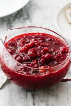 a glass pitcher filled with cranberry sauce on top of a table