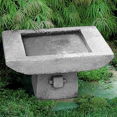 a concrete fountain in the middle of a garden