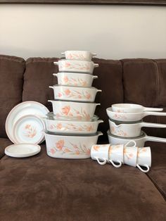 a stack of white dishes sitting on top of a brown couch