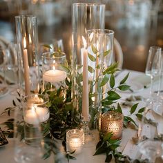 candles and greenery are arranged on the table for an elegant wedding reception or special event