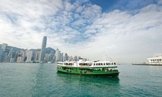 two green and white ferry boats in the water with city skyline behind them on a cloudy day