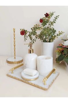 white and gold bathroom accessories with flowers in the background