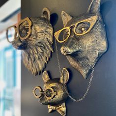 three wall mounted animal heads with glasses on it's face and chains around them