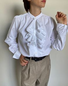 "White Cotton Blouse for Women Size 10 | Ralph Laurent White Blouse with Ruffled Front and French cuffs. Composition: 100% cotton. Size on tag: 10 Measurements of the vintage white blouse lying flat: chest: 51 cm | 20.1\" length: 65 cm | 25.6\" sleeves: 60 cm | 23.6\" shoulder to shoulder: 38 cm | 15\" In excellent vintage condition.  The model wearing this classic white blouse is 1,68 m | 5.5 foot tall; Chest: 88 cm | 35\", waist: 68 cm | 26\", hips: 88 cm | 35\".  The beige herringbone pants i Cotton Shirt With Ruffle Sleeves, Cotton Ruffle Sleeve Blouse For Work, Classic Formal Shirt With Ruffles, Elegant Ruffle Sleeve Cotton Blouse, Elegant Cotton Blouse With Ruffle Sleeves, Cotton Ruffle Tops For Work, Cotton Blouse With Ruffled Collar For Work, Elegant Cotton Tops With Ruffled Collar, Classic Ruffled Blouse For Daywear