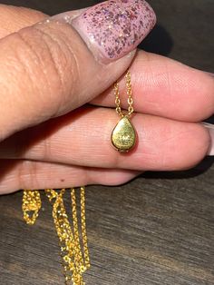 a woman's hand holding a tiny gold necklace