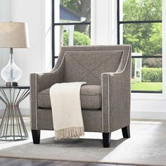 a living room scene with focus on the arm chair and side table that has a lamp