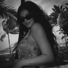 a woman wearing sunglasses standing in front of palm trees