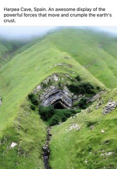 an open pit in the side of a green mountain with grass growing on it's sides