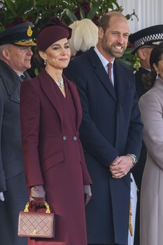 the queen and prince are standing next to each other in front of people wearing hats