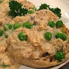 a white plate topped with meat and peas covered in gravy next to parsley