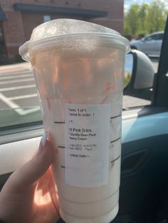 a person holding up a plastic cup with information on it in the back seat of a car