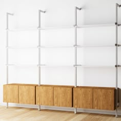 an empty white room with shelves and wooden drawers on the wall, in front of a wood floor