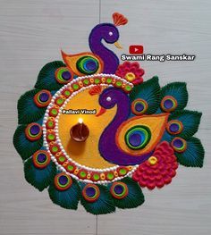 a colorful peacock design on a white wooden surface with a lit diya candle in the center