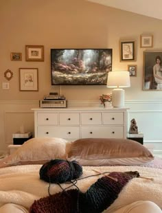 a bedroom with a bed, dresser and pictures on the wall above it is shown