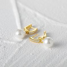 Indulge in the allure of these classic pearl earrings, as they effortlessly elevate any outfit with their refined beauty. These exquisite earrings feature detachable pearl pendants, allowing you to customize your look effortlessly. The hoops are adorned with sparkling white stones, adding a touch of brilliance to your ensemble. Whether worn as a sophisticated statement piece or as a delicate accessory, these earrings are sure to captivate attention and enhance your natural elegance. Embrace the Elegant Hoop Earrings With Pearl Charm, Classic Pearl White Hoop Earrings, Classic Pearl White Pearl Hoop Earrings, Classic Elegant Design Pearl Earrings, Classic Elegant Pearl Earrings, Classic Bridal Earrings In Pearl White With Pearl Charm, Classic Pearl White Bridal Earrings With Pearl Charm, Elegant Dangle Hoop Earrings With Pearl Drop, Elegant Dangle Pearl Drop Hoop Earrings