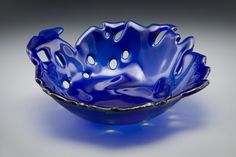 a blue bowl with holes in the center on a white background, it is also used as a serving dish