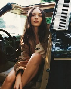 a woman sitting in the driver's seat of a car with her legs crossed