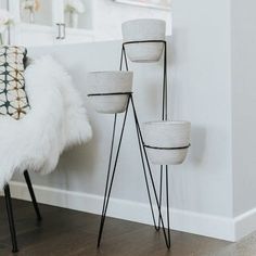 three white planters sitting on top of a wooden floor next to a chair and mirror